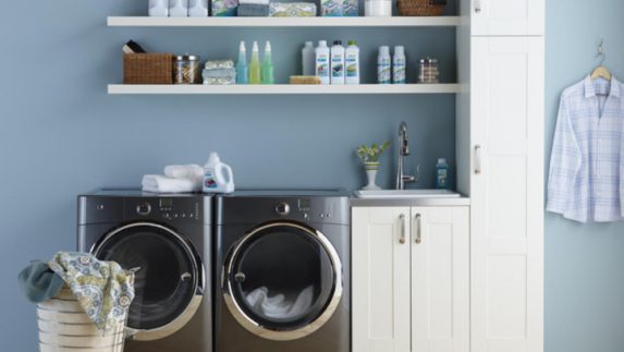 A laundry room with an energy-efficient washer and dryer and shelves containing Amway Home care products. Even with biodegradable, phosphate-free laundry and home cleaning formulas that perform as well as or better than typical products, Amway scientists keep working to improve them!