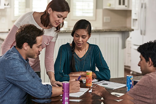 Men and women working at a table with XS Energy Drinks