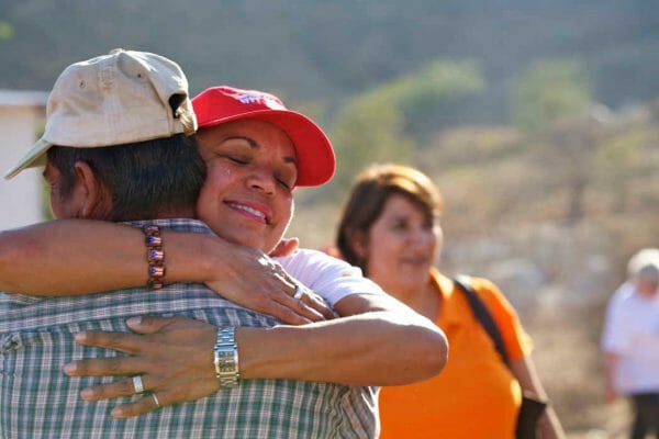 Amway employee hugging local resident on Habitat site in Central America.