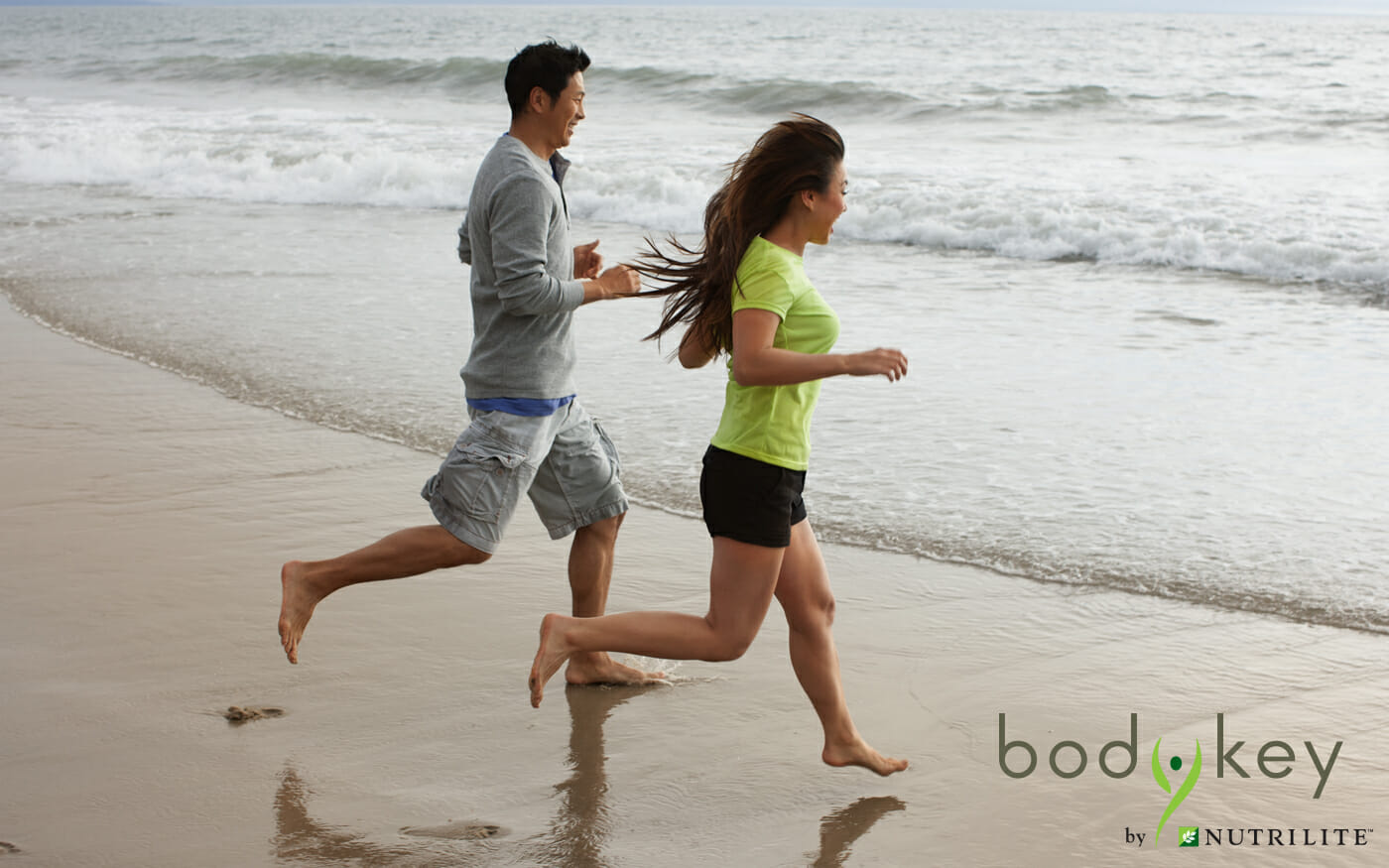 Man and woman running on a beach towards the water