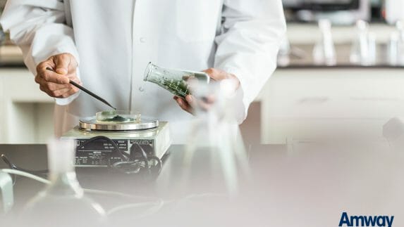 Man in lab coat weighing green powder