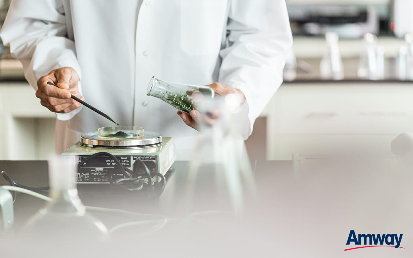 Man in lab coat weighing green powder