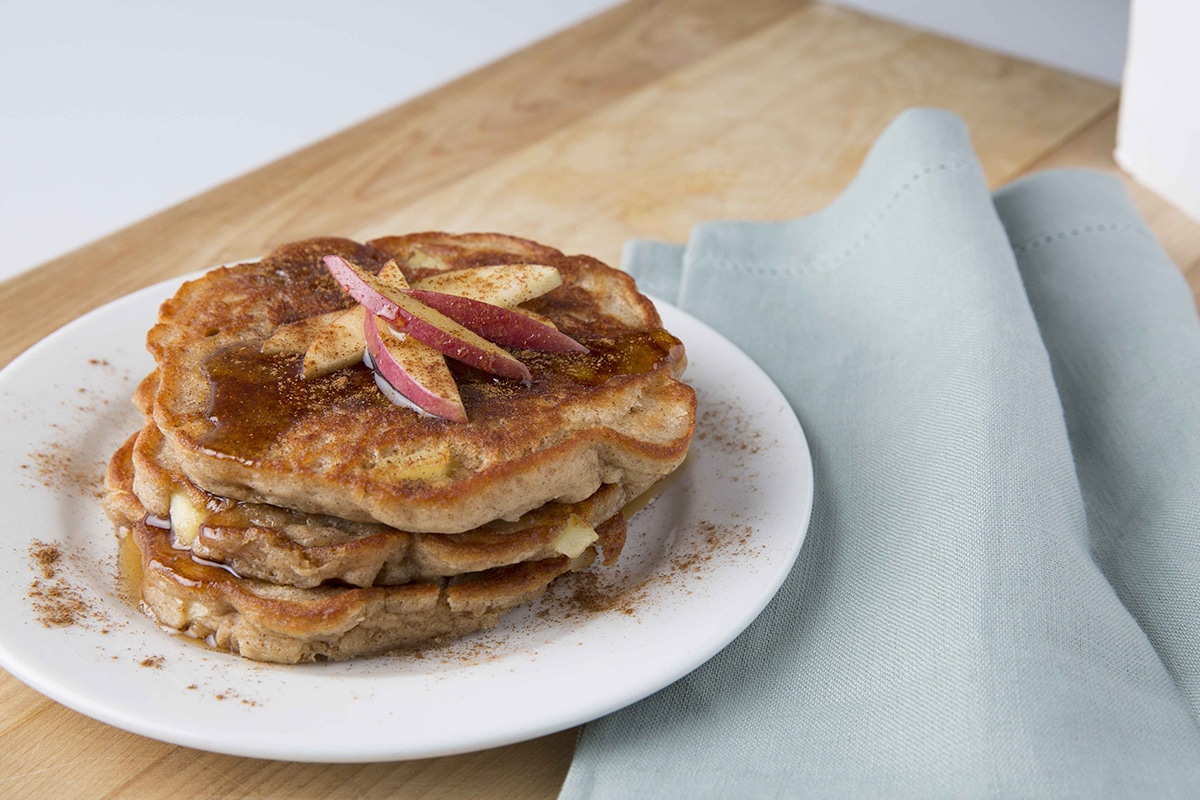 Stack of pancakes with cinnamon and apple slices on top