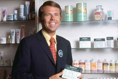 Historical Image of Dr. Sam Rehnborg holding Nutrilite products