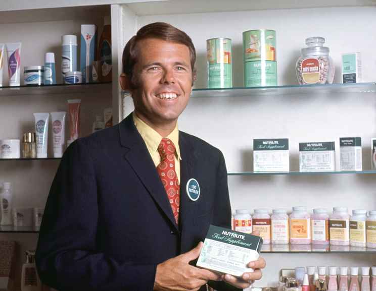 Historical Image of Dr. Sam Rehnborg holding Nutrilite products