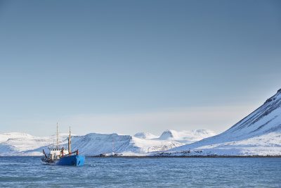 Large ship on the water with large snowy hills in the background