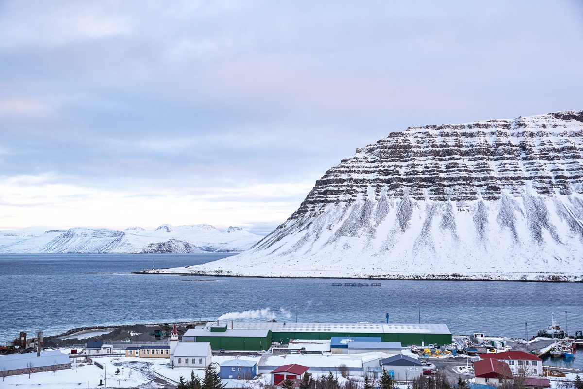 Town of Bildudalur with a large body of water and large snowy hills in the background