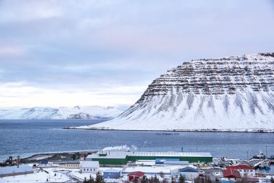 Town of Bildudalur with a large body of water and large snowy hills in the background