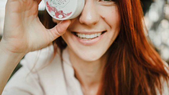 Woman holding Ruth Bina puck in front of her eye