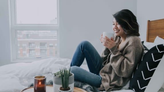 Woman sitting in bed with a coffee mug