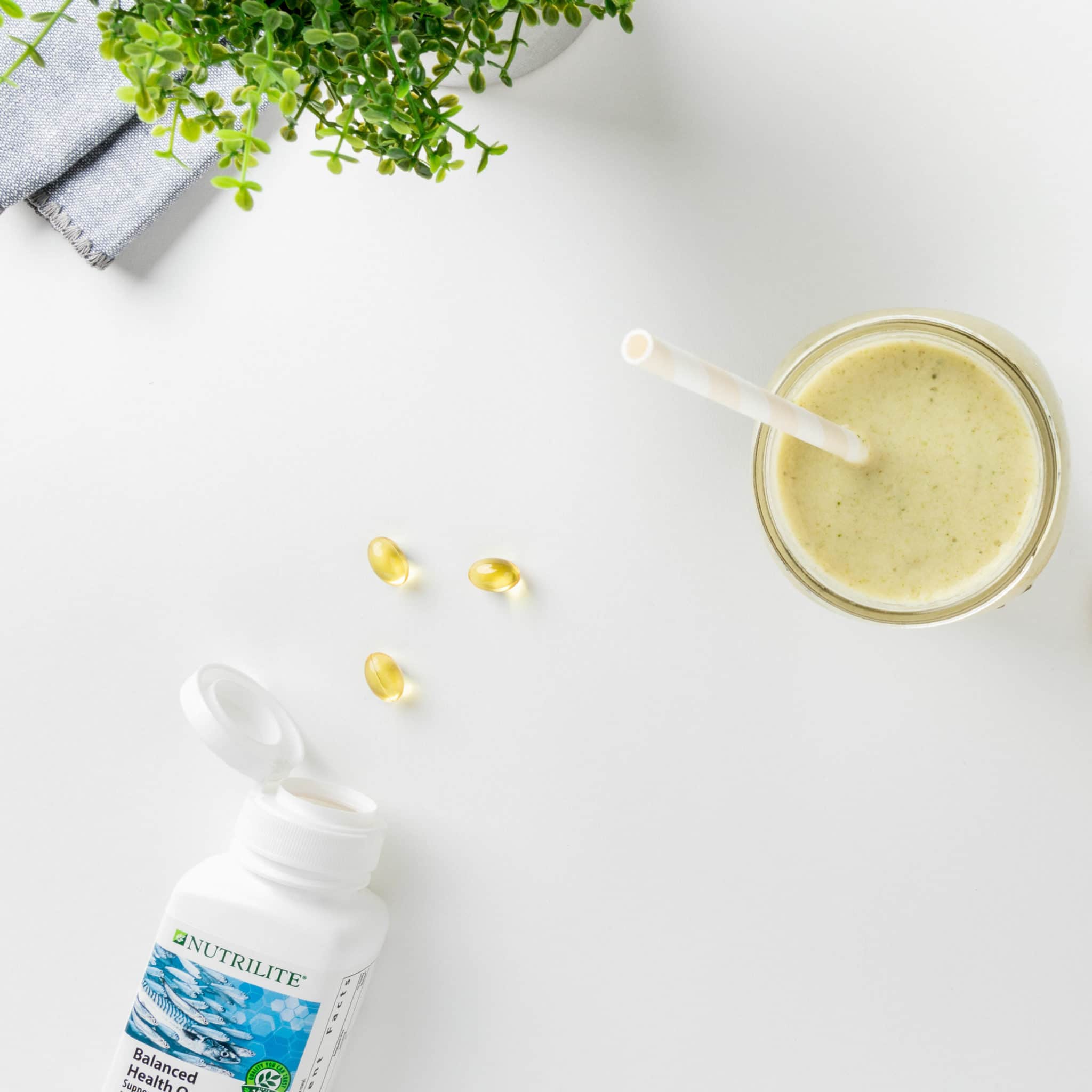A close up image of an open bottle of Balanced Health Omega gel caps next to a smoothie in a glass with a straw. Omega-3 fatty acids help support the health of our nervous and cardiovascular systems, while protein helps us grow and repair our cells.