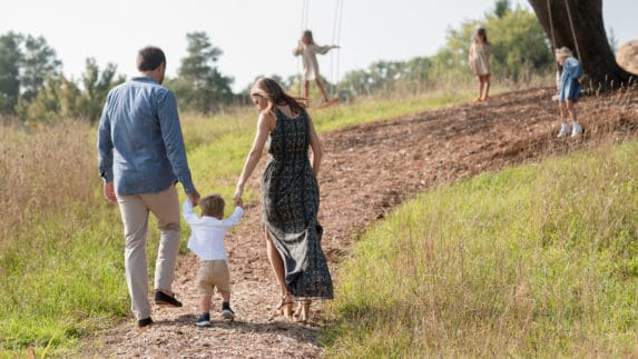 Parents walking with child while other children play