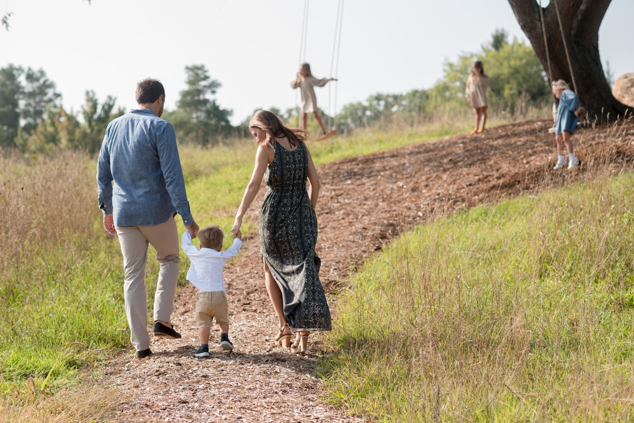 Parents walking with child while other children play