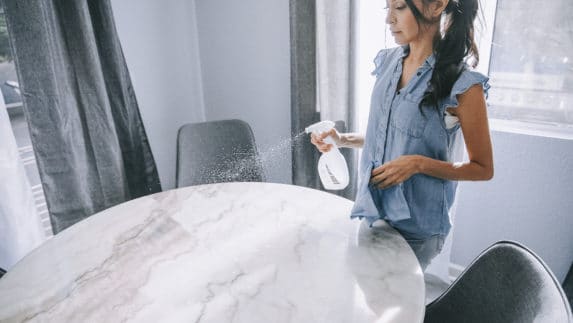 Woman spraying a table to clean it