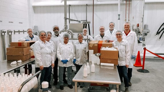 Amway employees wearing hairnets prepare products to donate