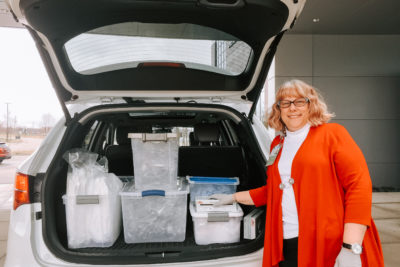 Amway employee standing next to plastic bins of personal protective equipment in the back of an SUV