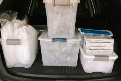 Plastic bins of personal protective equipment loaded in the back of an SUV