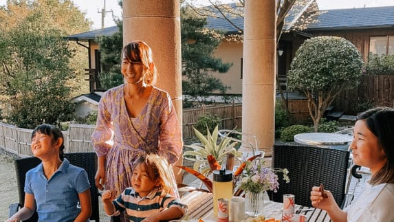 Two women and two girls smile sitting at a table outdoors