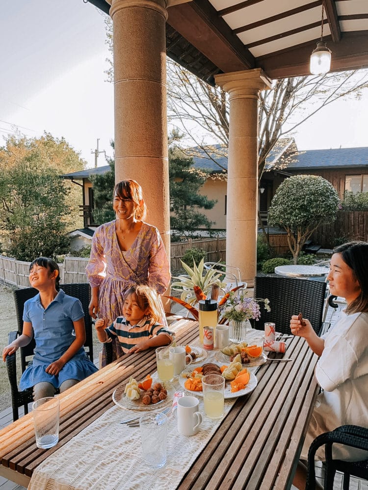 Two women and two girls smile sitting at a table outdoors