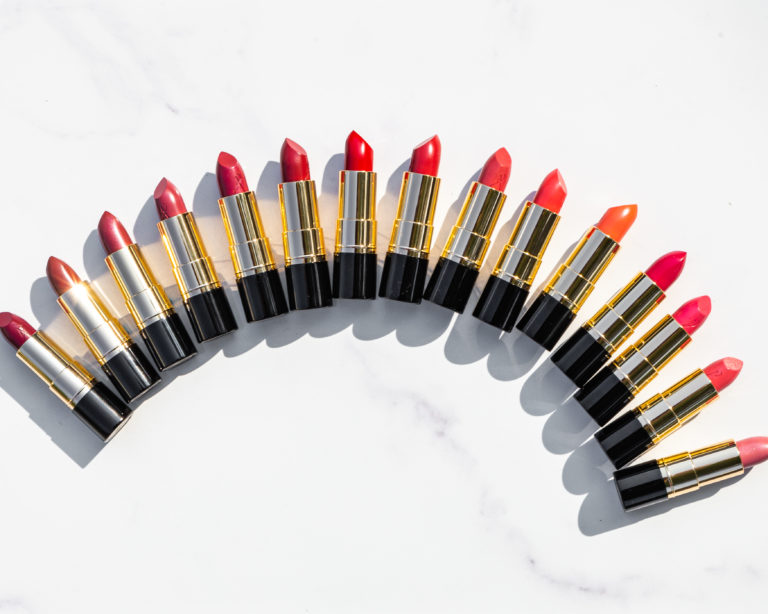 15 different colored artistry studio lipsticks without their caps off aligned in a curve