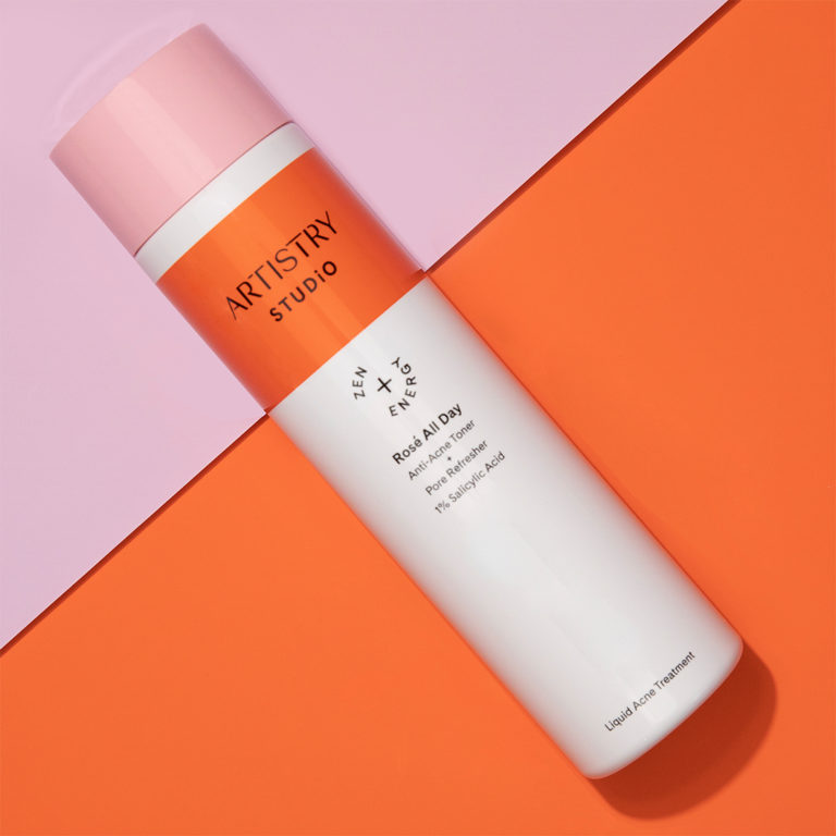 A bottle of artistry studio Rosé all day anti-acne toner sitting on a half pink and half orange surface
