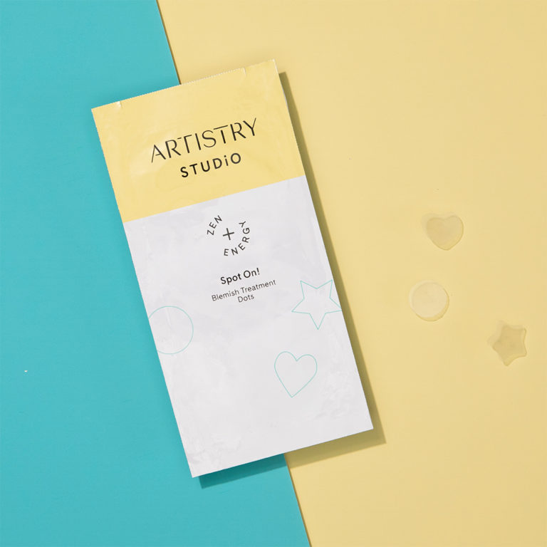 Packet of artistry studio spot on! blemish treatments sitting on a half teal half yellow surface with three of the dots sitting on the yellow side.