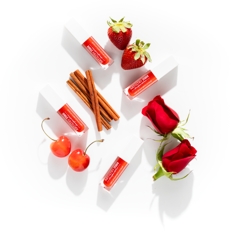Four artistry studio shanghai edition lip glosses with cinnamon sticks. strawberries, roses, and cherries around.