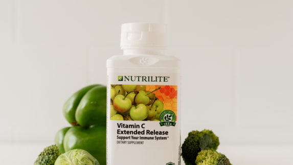 Bottle of Nutrilite Vitamin C Extended Release supplements surrounded by vegetables