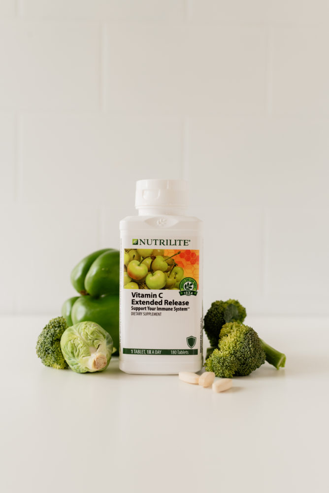 Bottle of Nutrilite Vitamin C Extended Release supplements surrounded by vegetables