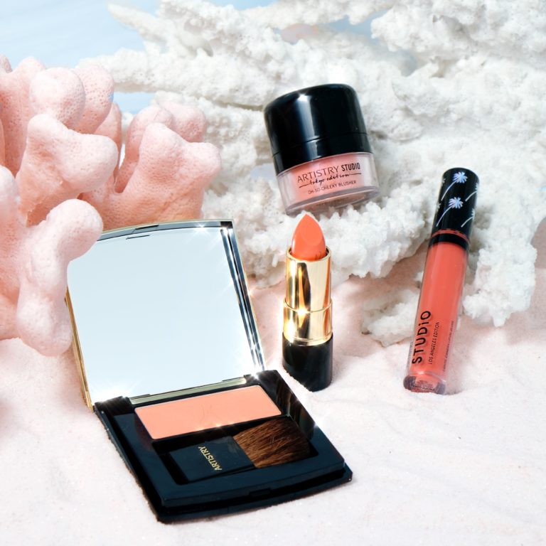 Four different artistry studio makeup products all in a coral color with white and orange colored coral in the background