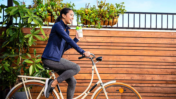 Woman riding a bike and holding a Bodykey bottle