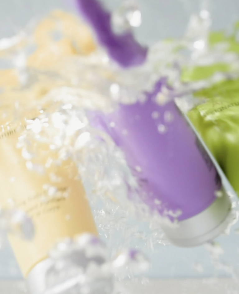 Blurry image of three artistry products being dropped into water