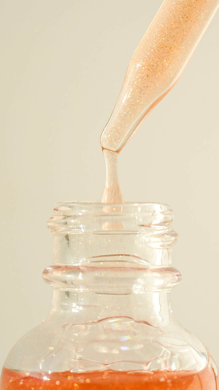 Closeup of a dropper dripping into a serum bottle