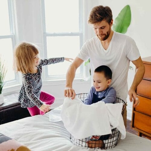 Dad folding laundry with young children