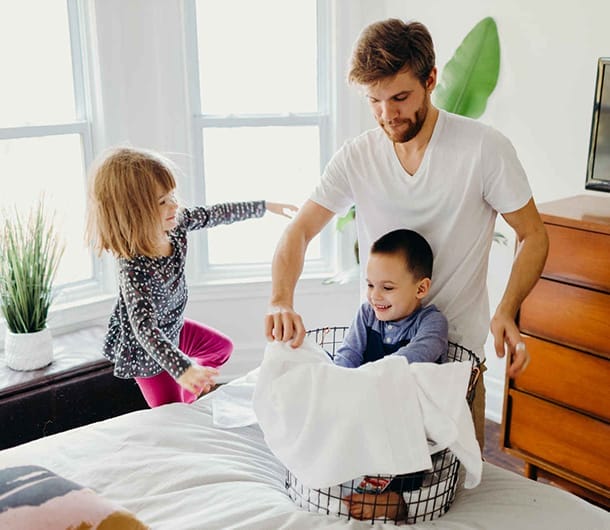 Dad folding laundry with young children